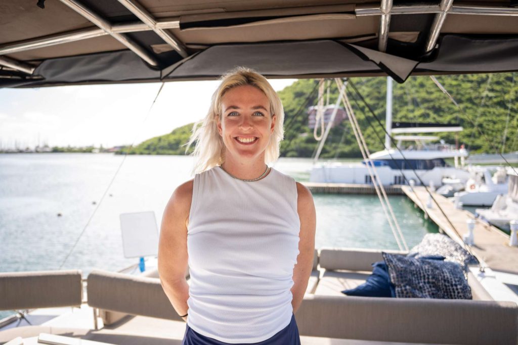 Smiling stewardess welcoming guests aboard a crewed charter yacht in the BVI
