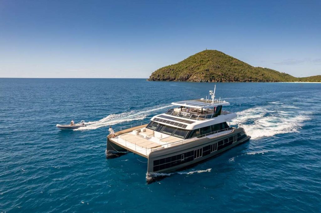 Crewed charter yacht cruising past a green island in the British Virgin Islands