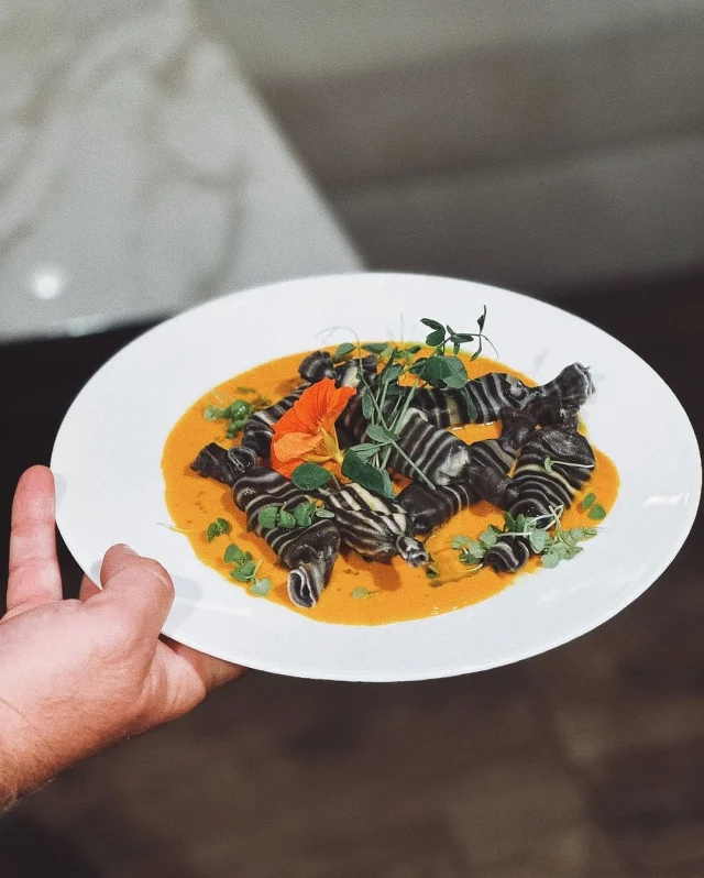 Lobster ravioli in clam bisque, served aboard charter yacht Unwavering. 🤤 

This dish was a labor of love—two-tone pasta made with squid ink, stuffed with local Bahamian lobster, topped with edible flowers and herbs from @bluefieldsfarms, and finished with a vibrant parsley oil.

Served with a fresh heirloom tomato and mozzarella salad, it was a five-star favorite with the guests! ⭐⭐⭐⭐⭐

Complements to the Chef @goodcookingwhatslooking 👩‍🍳